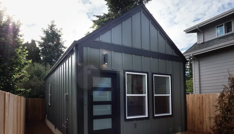A dark green board-and-batten detached ADU behind a cedar fence, built by Harris & Sons