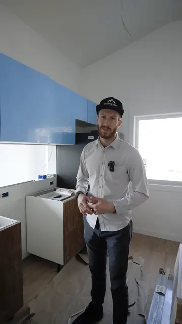 A Harris & Sons team member inside an ADU under construction, with blue kitchen cabinets going in