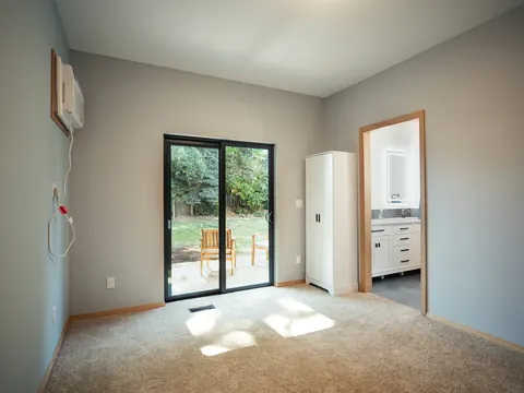 Inside a finished ADU: carpeted room with a sliding patio door
